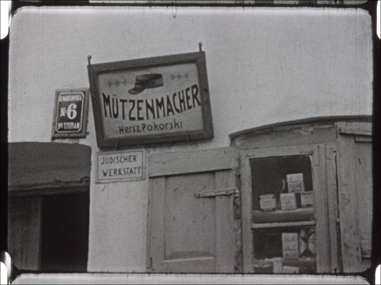 This event poster shows a film still depicting the front of the store of a Jewish hatter in the Nazi Province of East Prussia