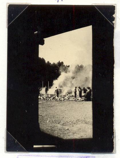 This event poster shows a photograph shot secretly through the gas chamber's doorway or window and showing the cremation of corpses in a fire pit.