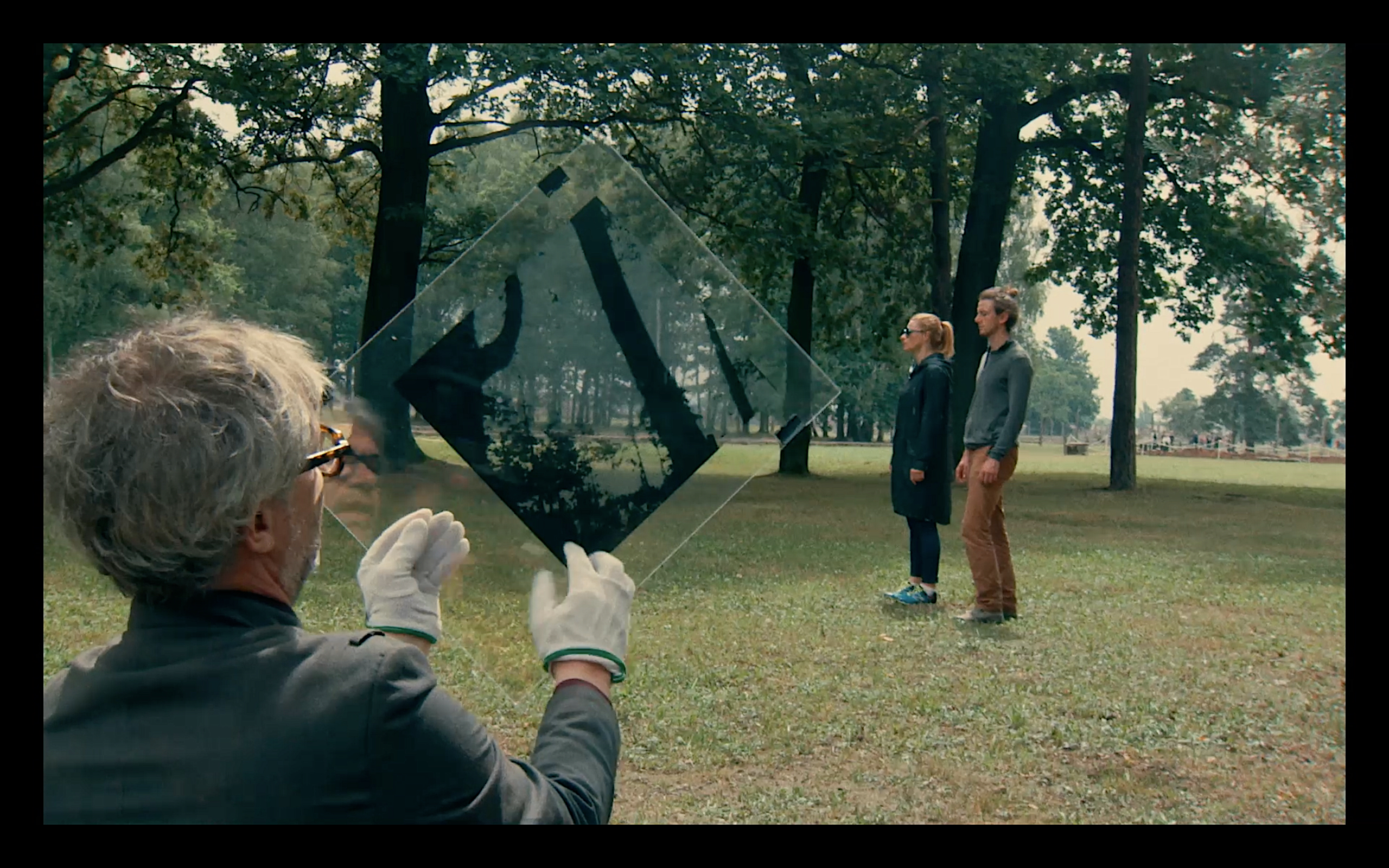 This event poster shows a film still depicting three people standing on a meadow with trees.